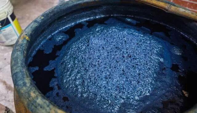 传习馆里的蓝靛染缸特写，缸面泛着深蓝的光